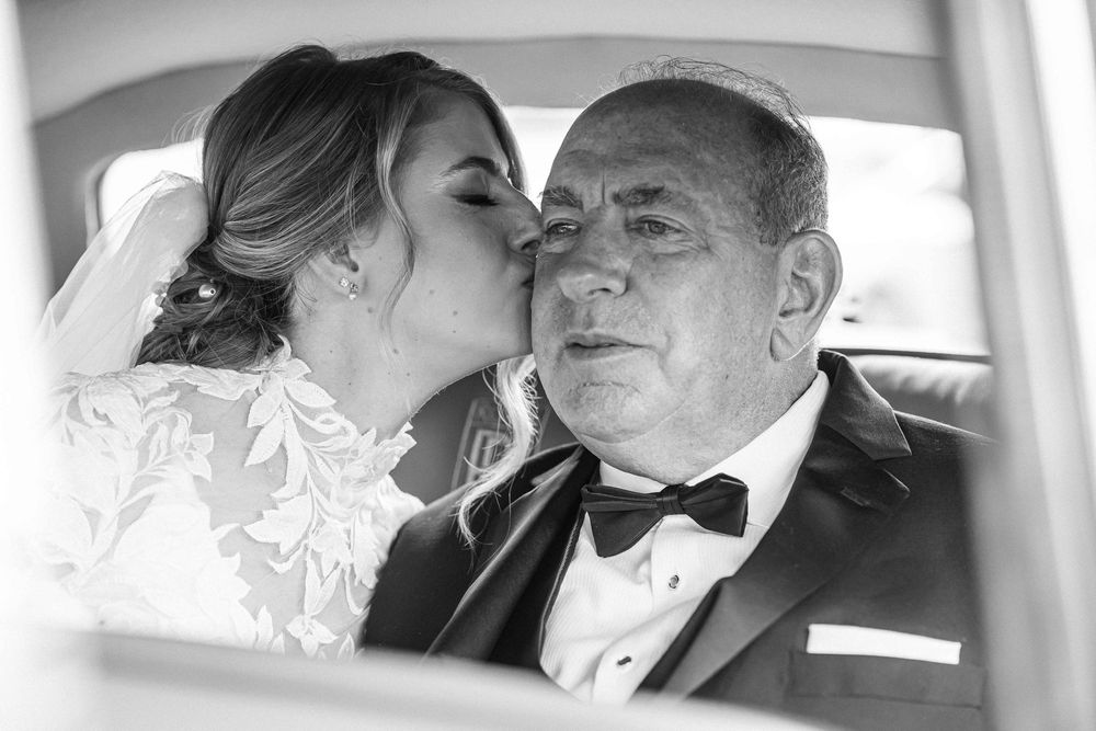 A tender moment captured through a car window during a wedding celebration.