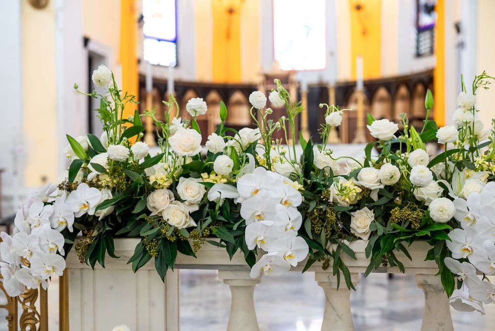 Elegant white orchids and roses arranged on pedestals create a romantic church altar decoration.