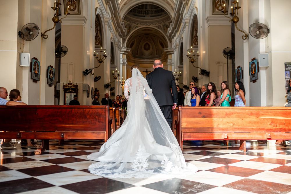 Long flowing veil trails down church aisle with checkered floor pattern.