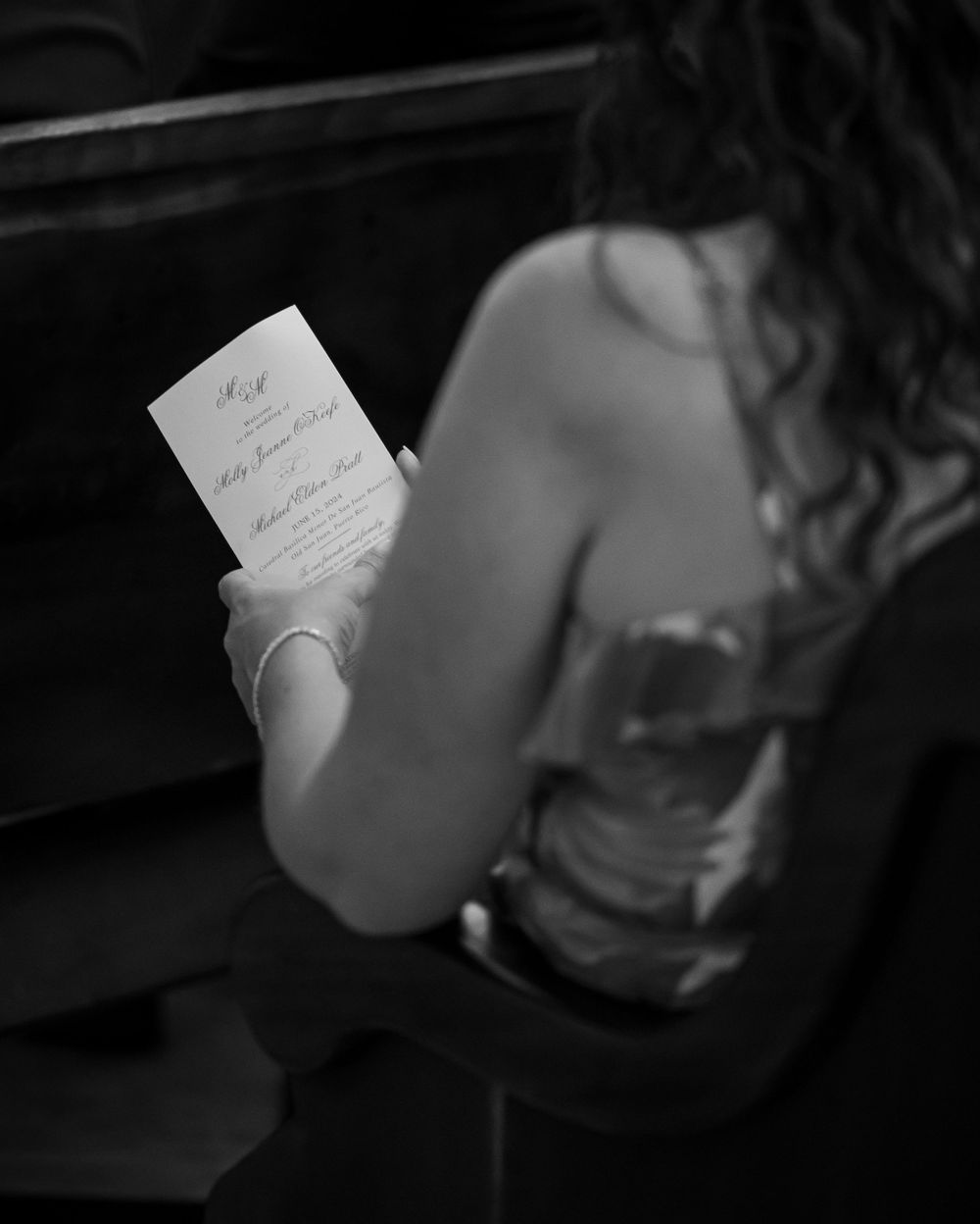 Black and white image of someone holding an elegant wedding invitation.