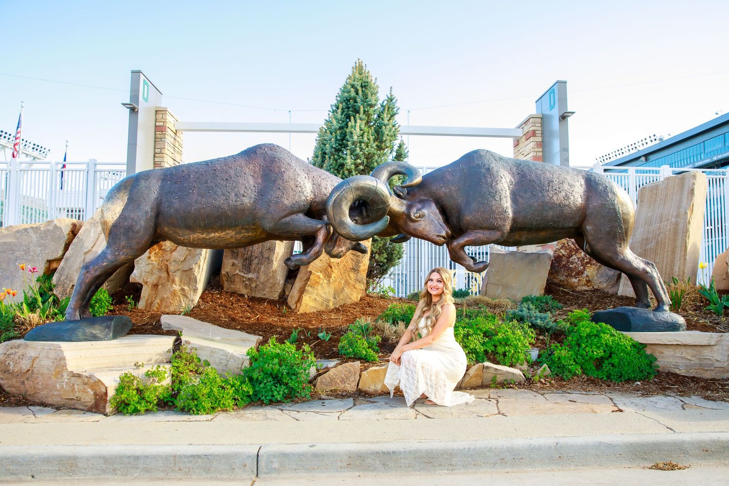 Graduate posing between large bull statues at outdoor monument.