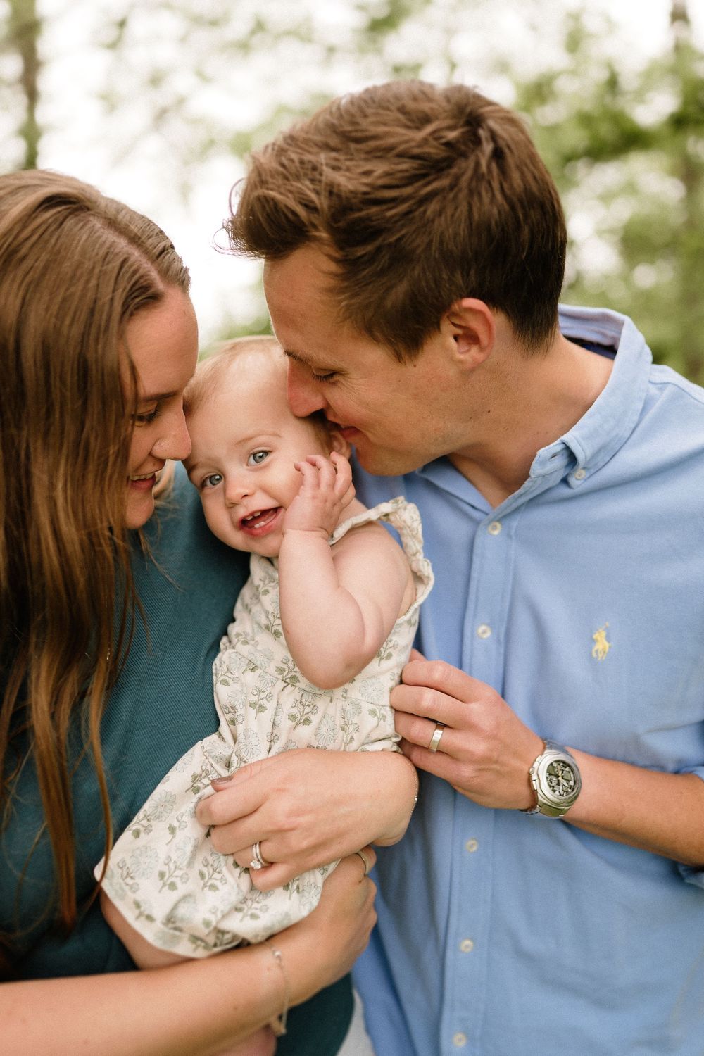 Happy family moment with parents embracing their smiling child outdoors.