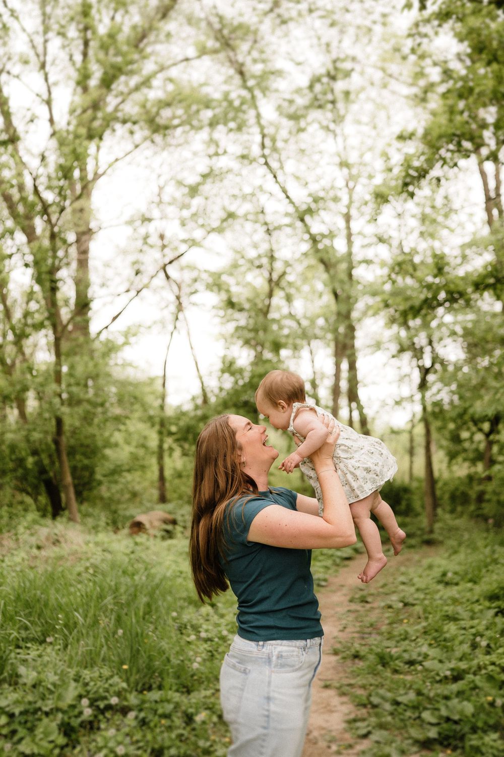 A tender moment between parent and baby while playing outdoors in a lush forest setting.