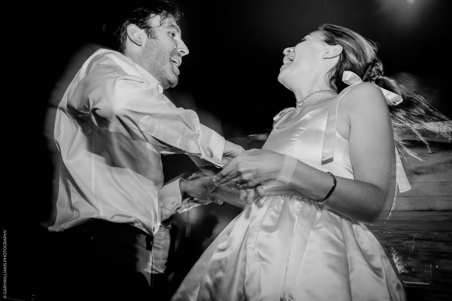 A joyful couple laughs together during their first dance at a black and white wedding reception.