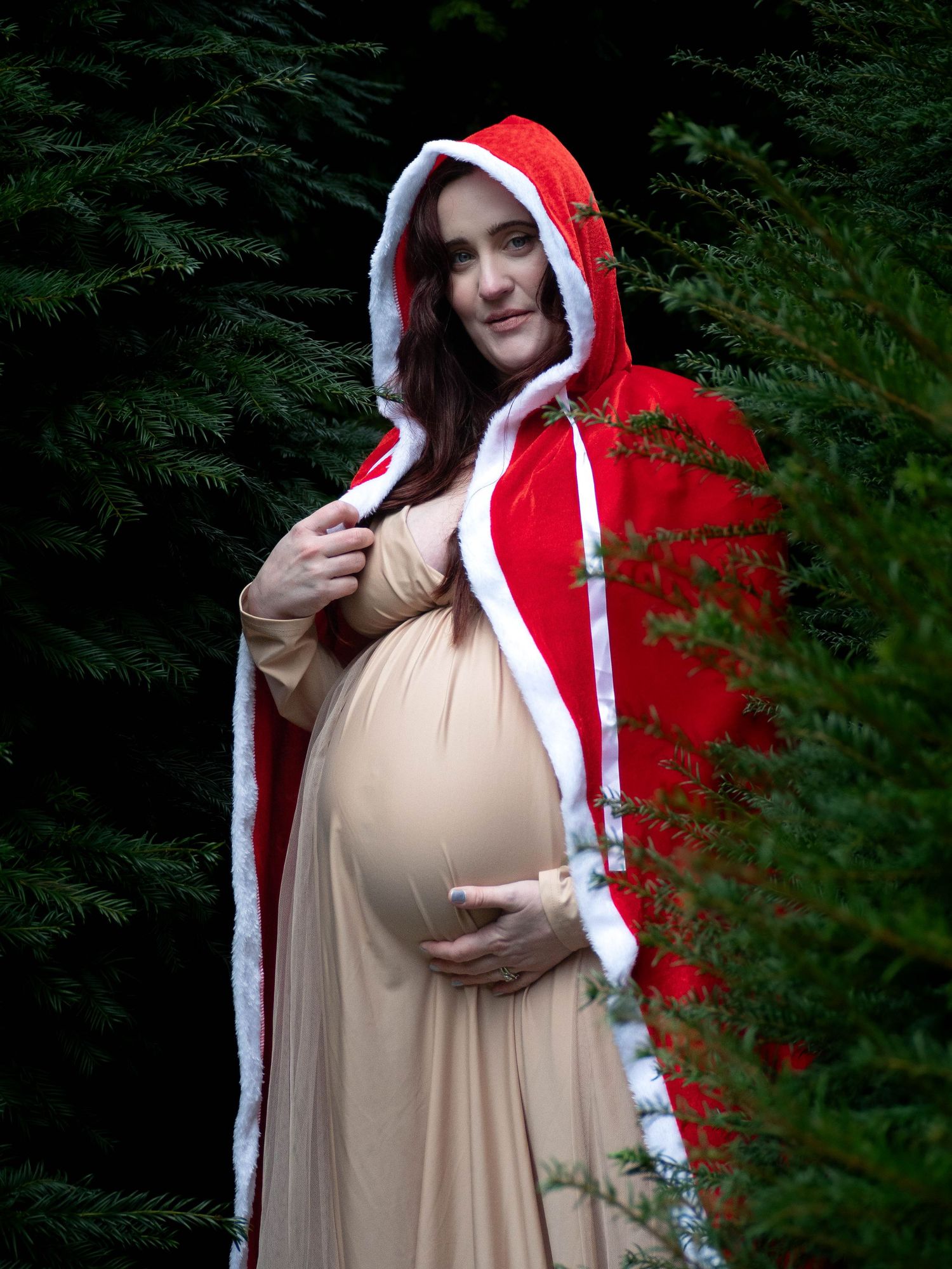 pregnant woman in newstead abbey gardens with santa cloak on