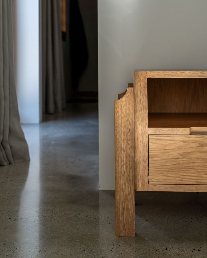 Interior design photograph of a luxurious high-end master primary bedroom with polished concrete flooring and custom bedside table
