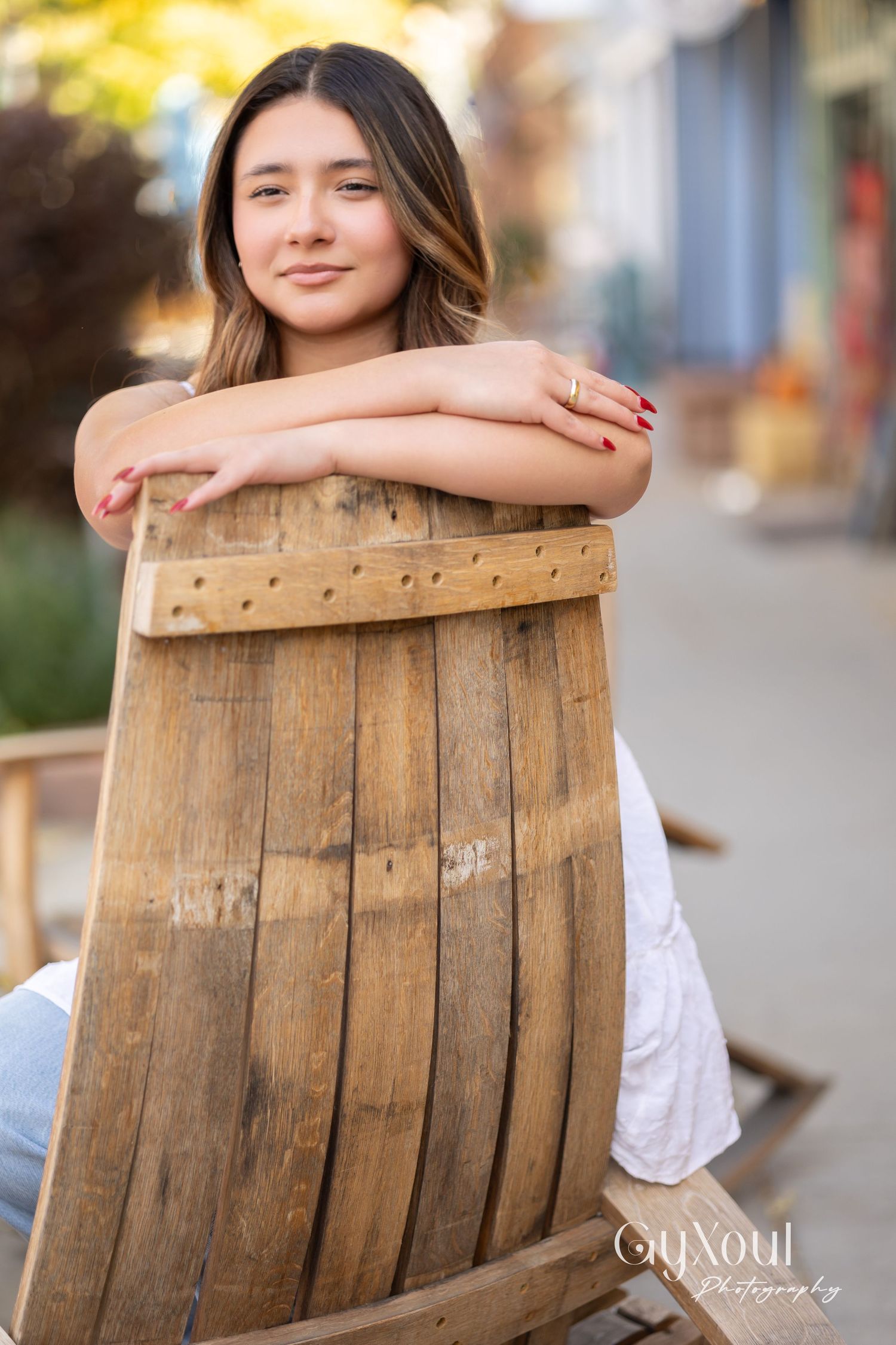 A person rests against a rustic wooden barrel outdoors with soft autumn lighting and a blurred background.