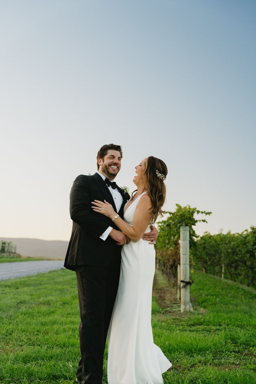 Joyful moment shared between newlyweds in vineyard setting.