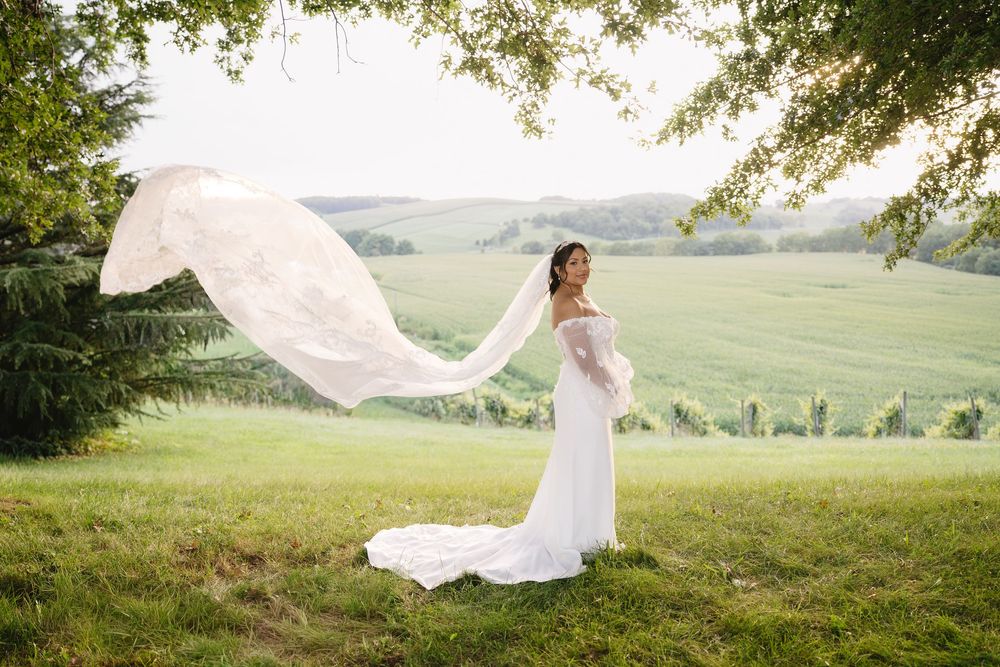Ethereal bridal portraits in a scenic meadow with flowing veil catching the wind at sunset.