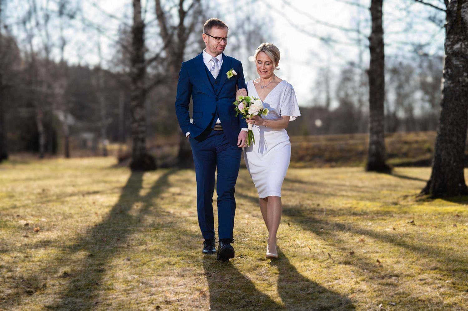 Hääpari kävelee keväisessä puistossa Turun kaksekerrassa.