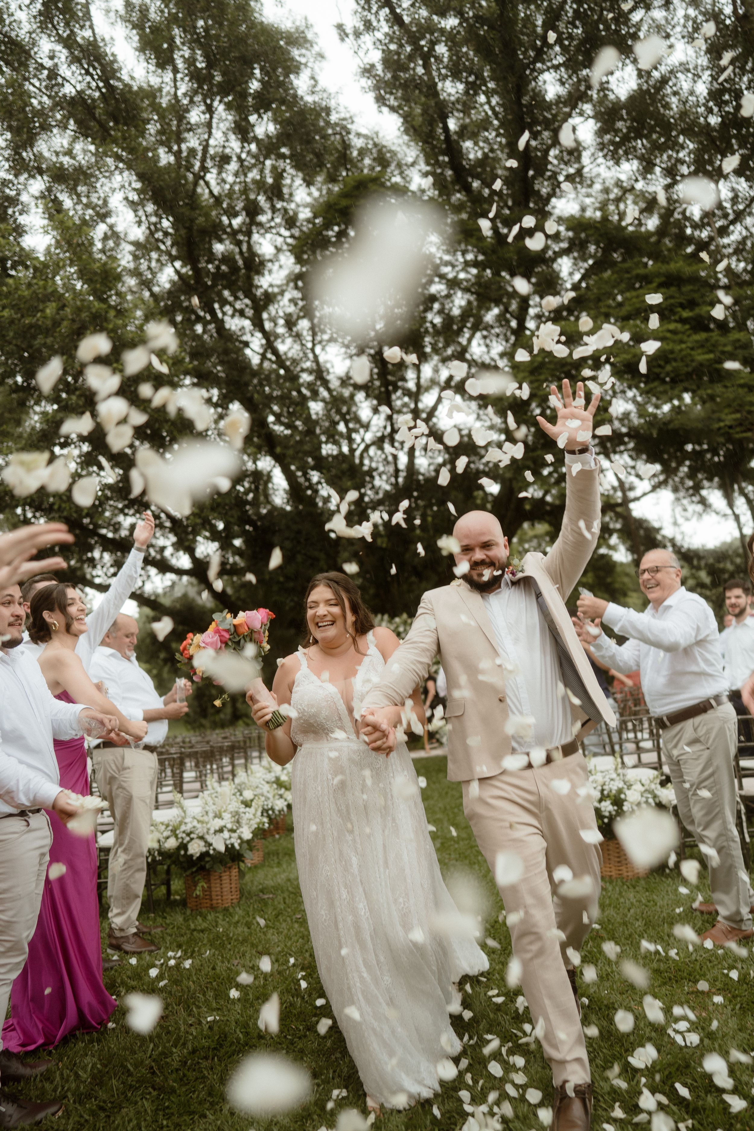 Wedding celebration sequence with flower petals being tossed in the air under trees.