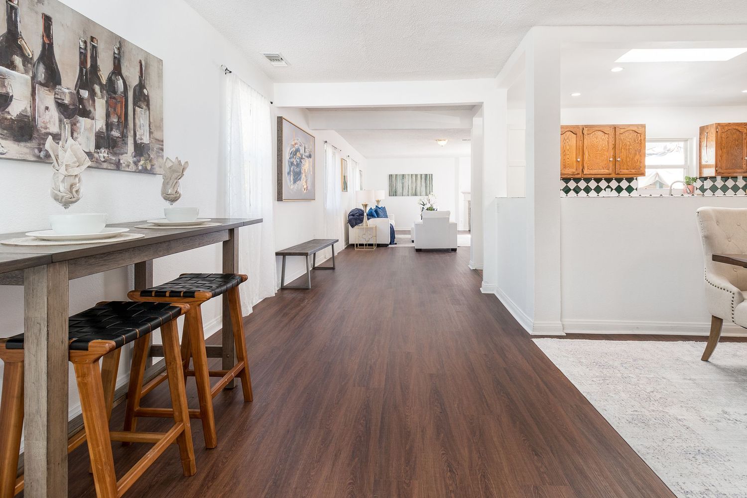 Bright open hallway with hardwood floors leading to kitchen and dining area.