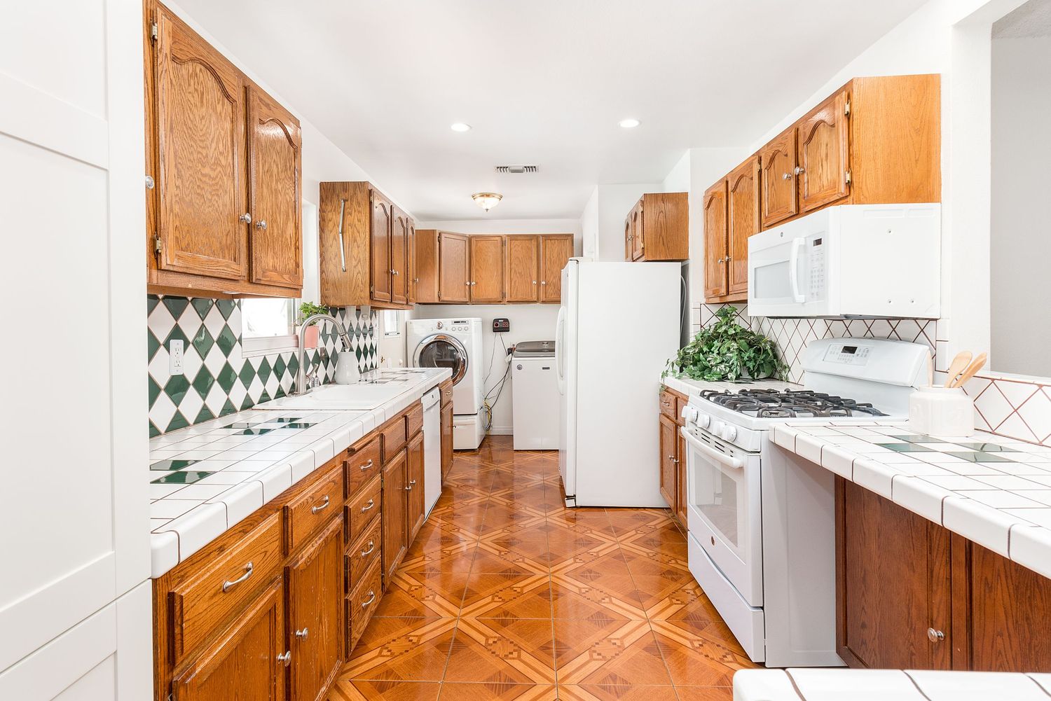 Spacious kitchen with honey oak cabinets, white countertops, and stainless steel appliances.