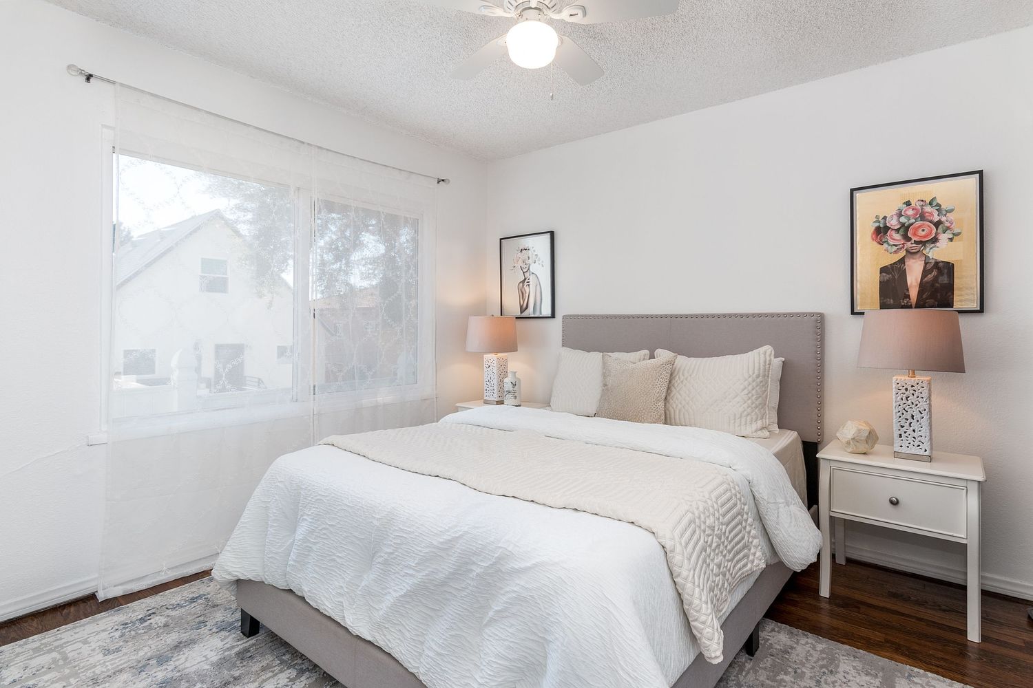 Minimalist white bedroom featuring a modern bed frame, bedside tables, and wall art.