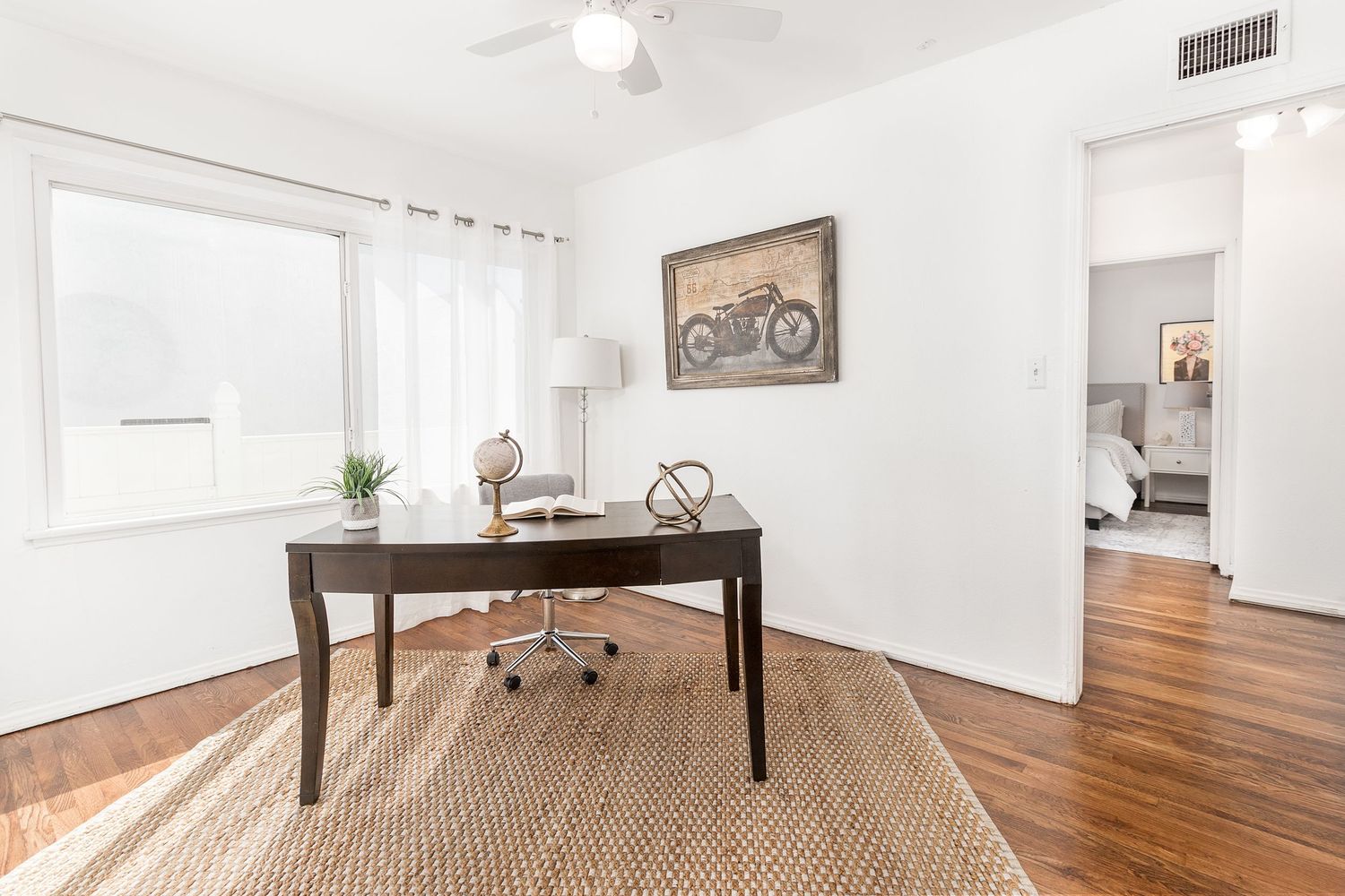 Spacious room with polished hardwood floors and white walls showcasing an open floor plan design.