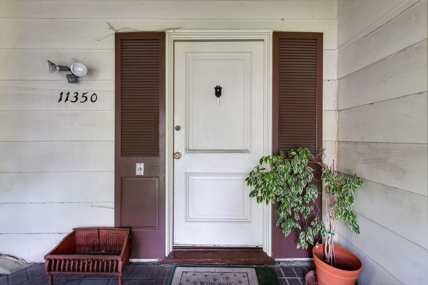 White exterior wall with brown doors and house number displayed.