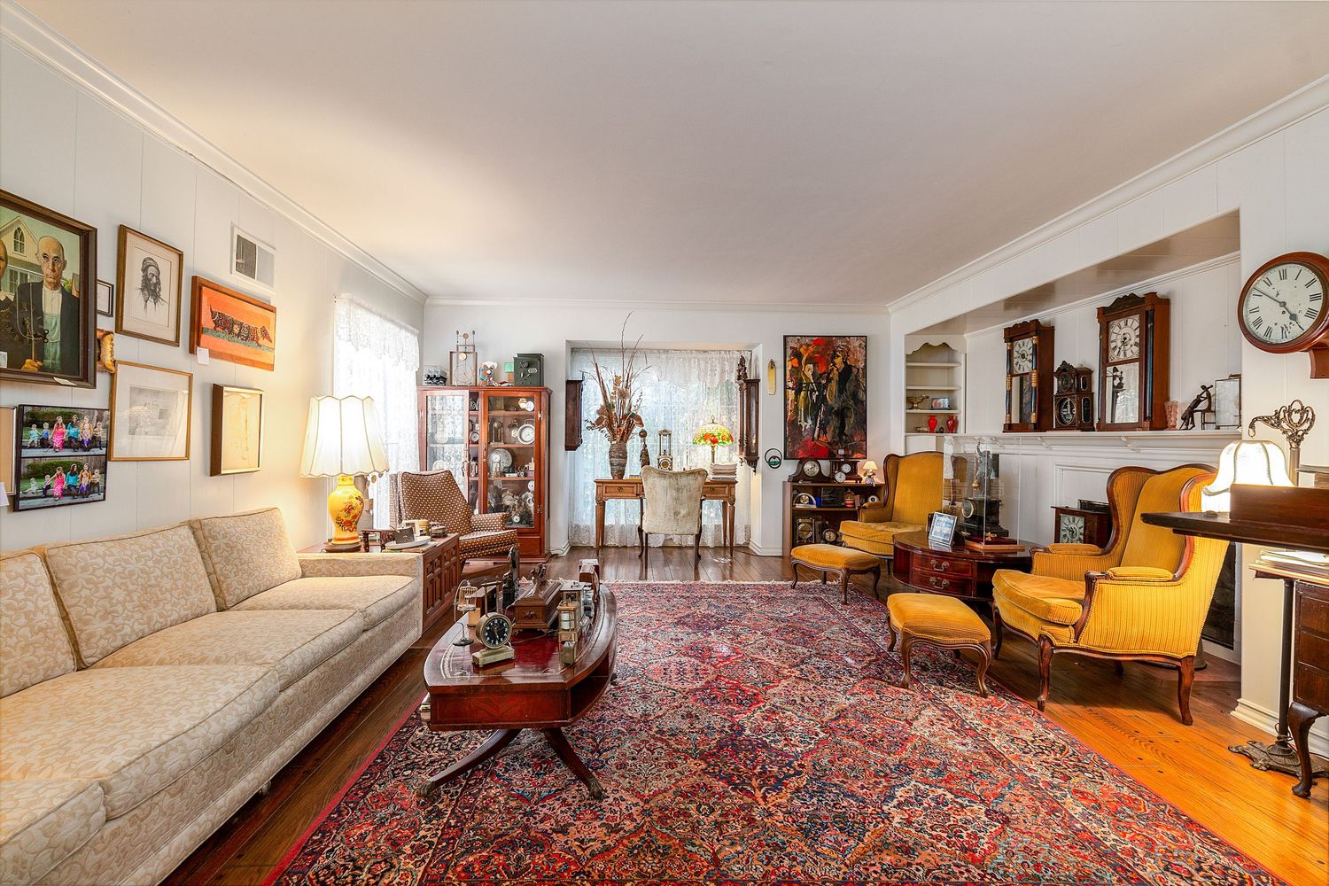 Spacious living room with ornate Persian rug, yellow accent chairs, and classic furniture arranged around white walls.