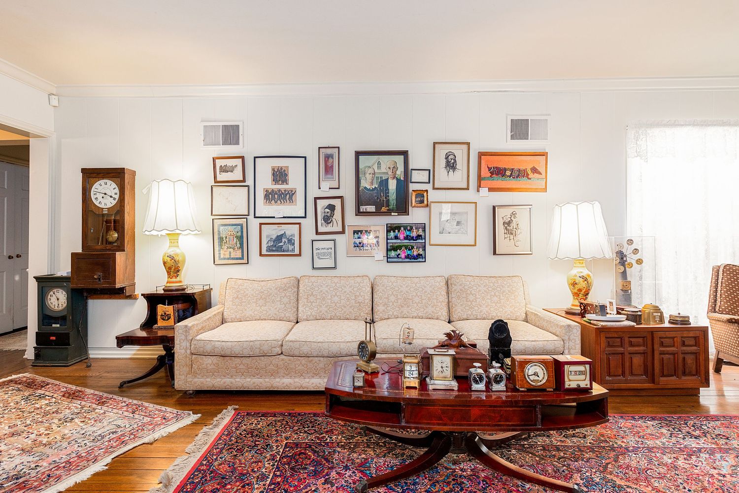 Modern living area with white sofa, gallery wall, and decorative red oriental rug covering hardwood floors.