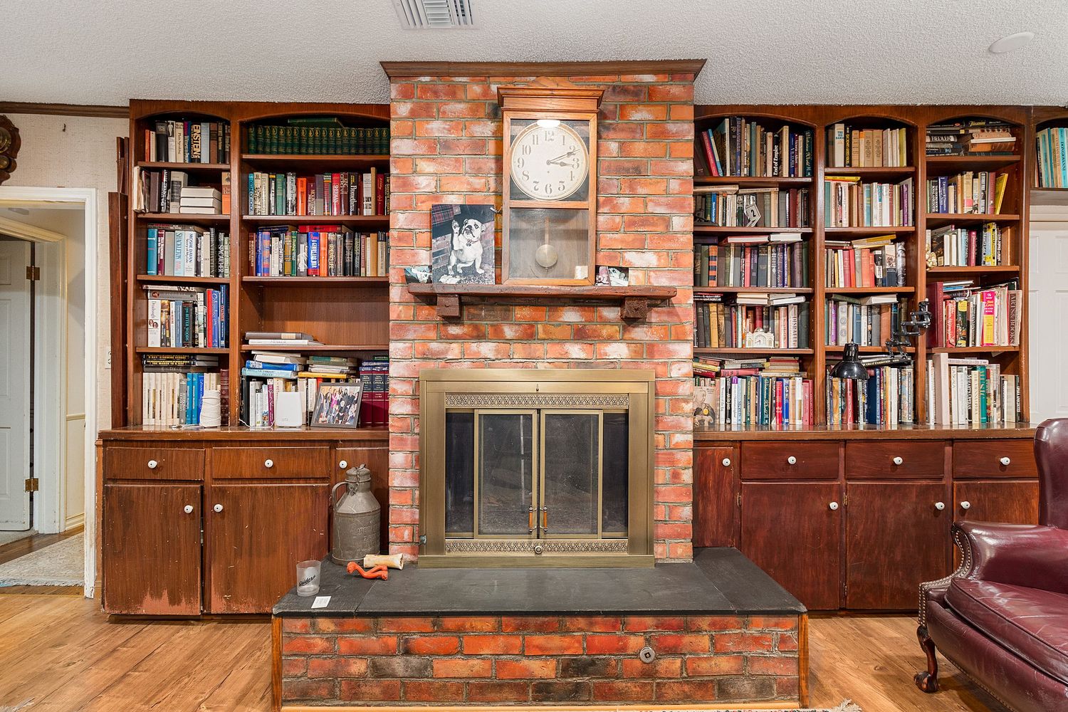 Custom wood library with floor-to-ceiling bookshelves against exposed brick walls.