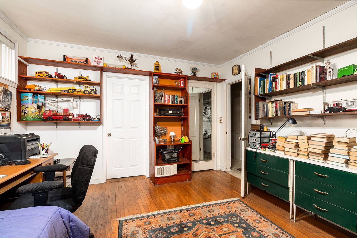 Open concept room with wooden shelving, green cabinets, and hardwood flooring.