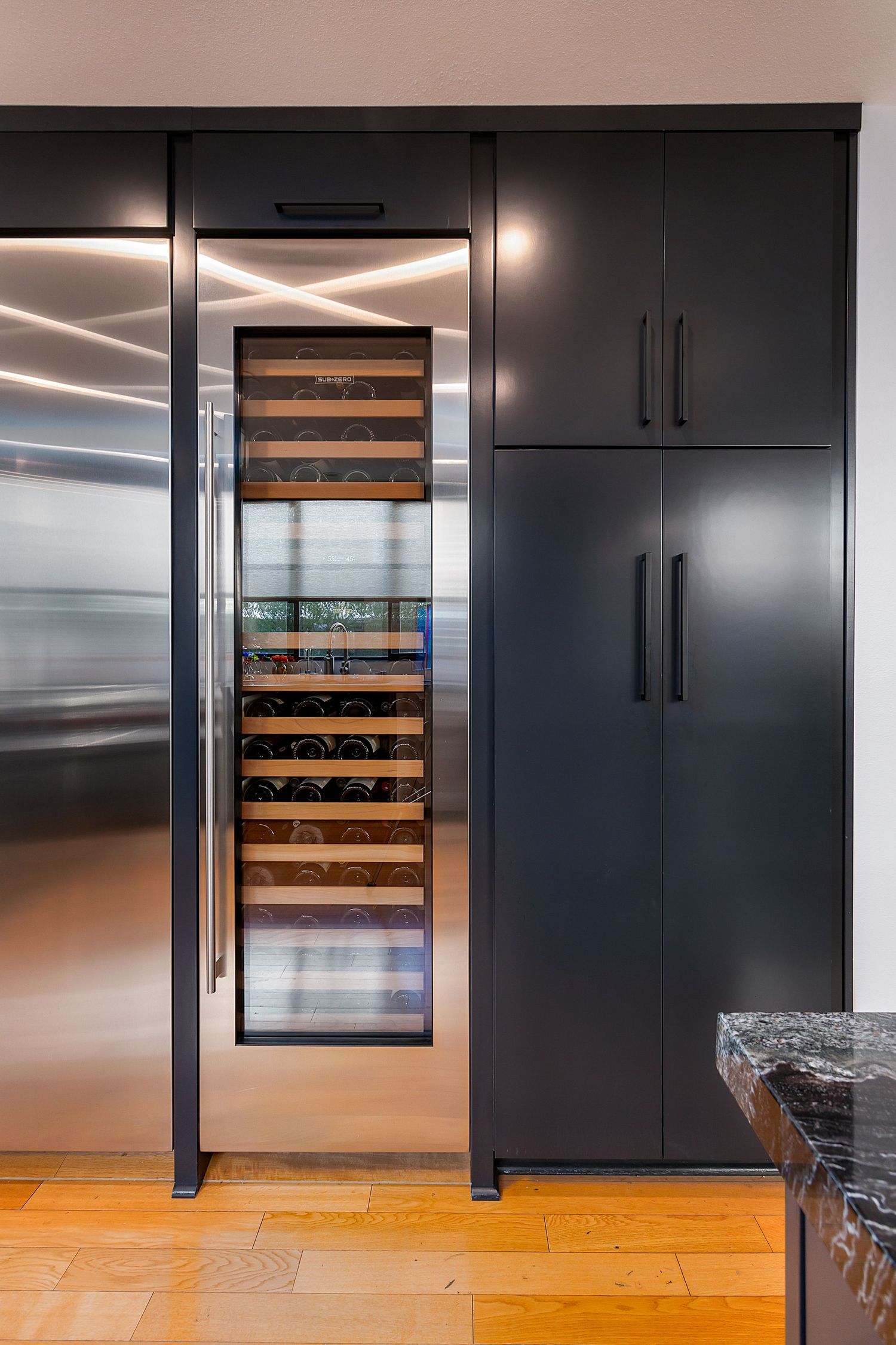 Built-in wine storage unit with temperature control flanked by dark cabinetry and hardwood flooring.