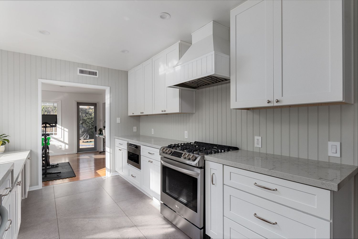 Contemporary white kitchen with sleek cabinetry, stainless appliances, and modern hardware.