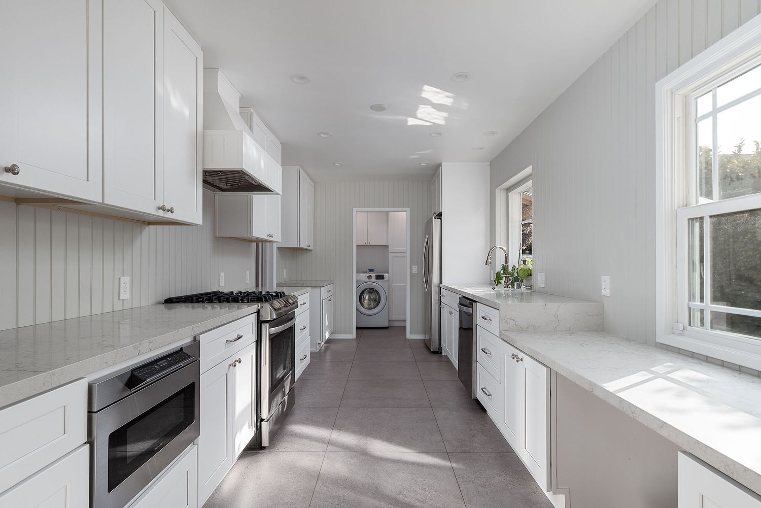 Bright white hallway with modern lighting fixtures and large windows.
