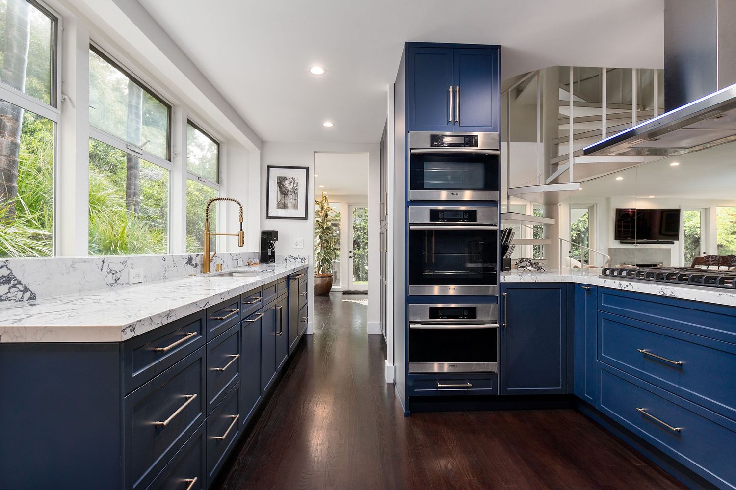 Luxurious kitchen with navy blue cabinets, white countertops, and stainless steel appliances.