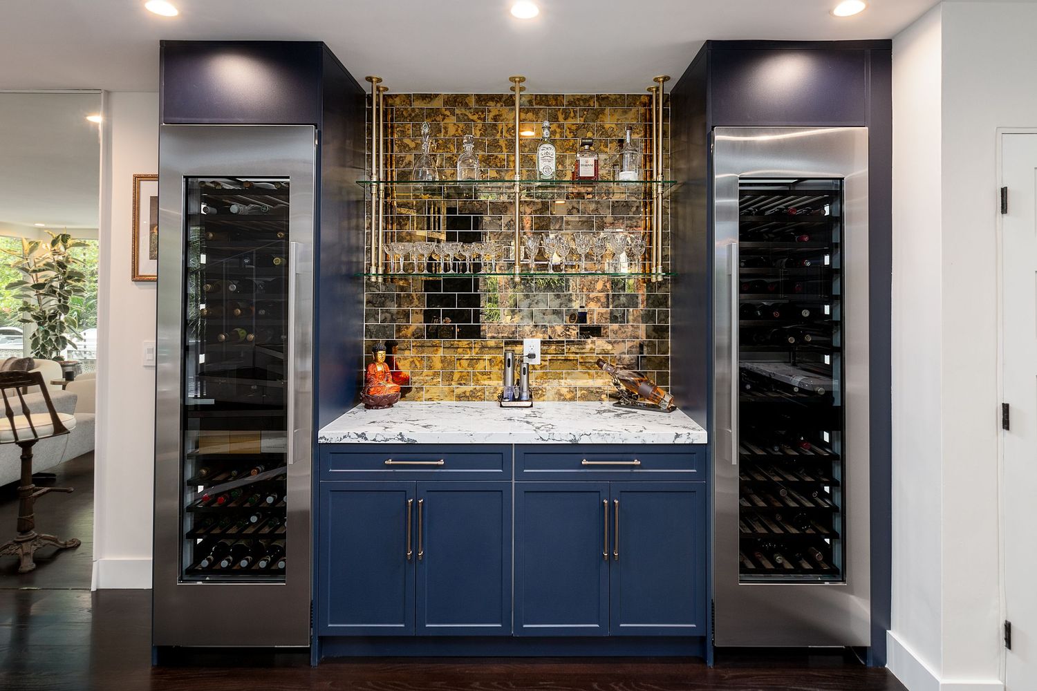 Custom bar area with illuminated glass shelving, wine storage, and navy blue cabinets.