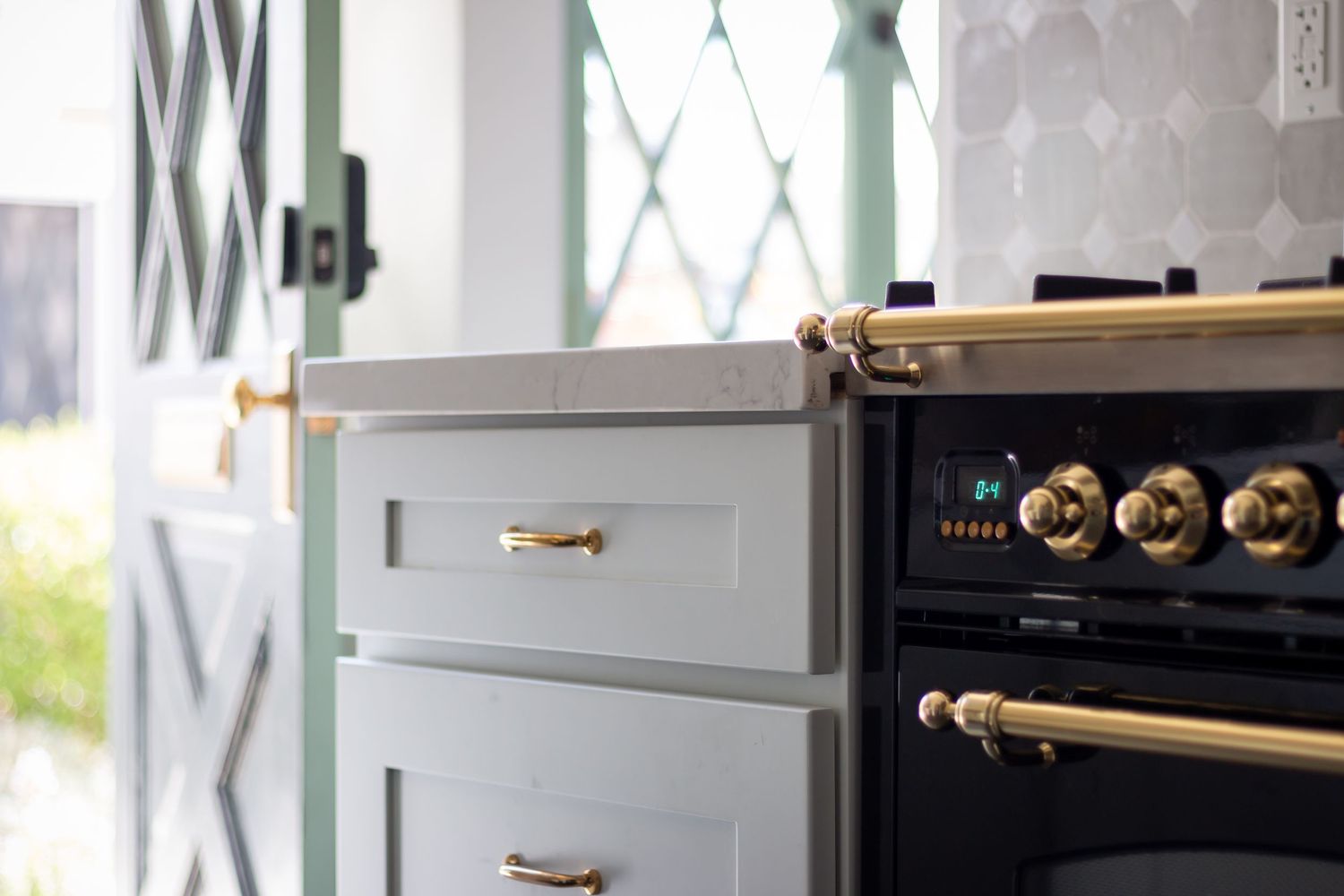 Close-up of kitchen cabinet hardware showing brass pulls against light gray cabinetry.
