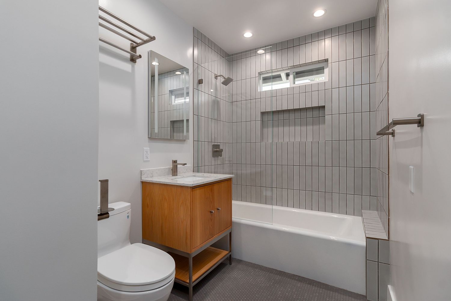 Contemporary bathroom with vertical tile walls, glass shower enclosure, and wooden vanity.