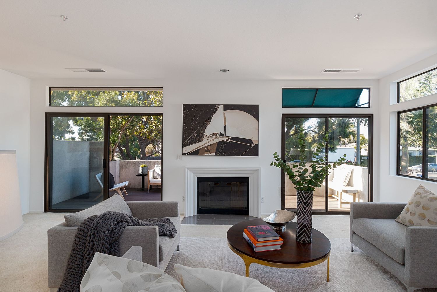 Open concept living area with modern gray furniture, white walls, and large windows.