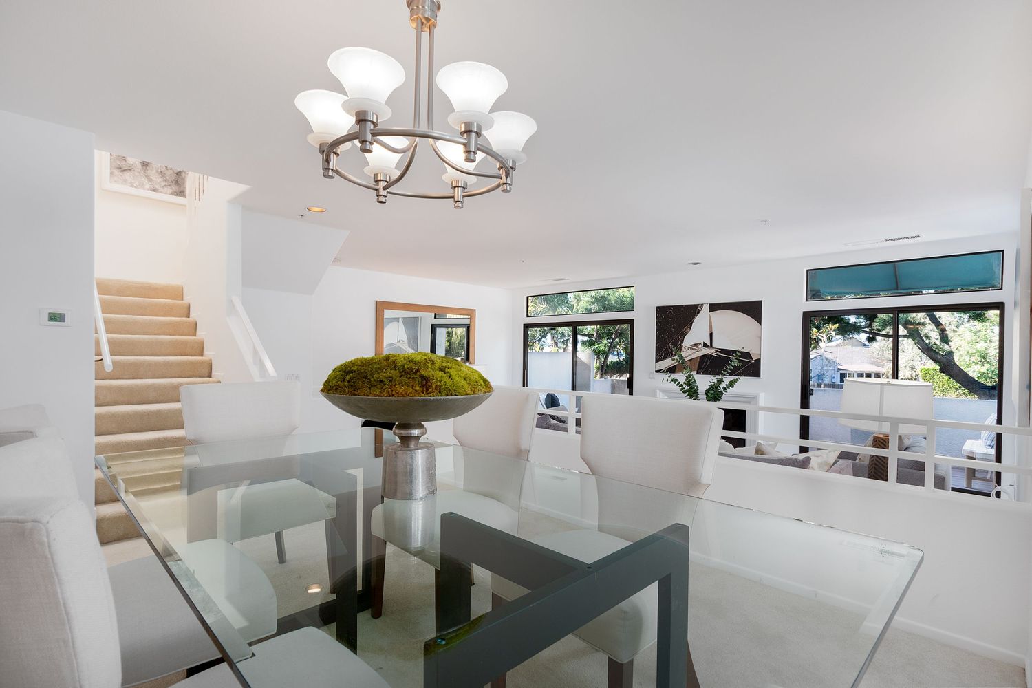 Bright white dining area with chandelier lighting and modern furnishings.