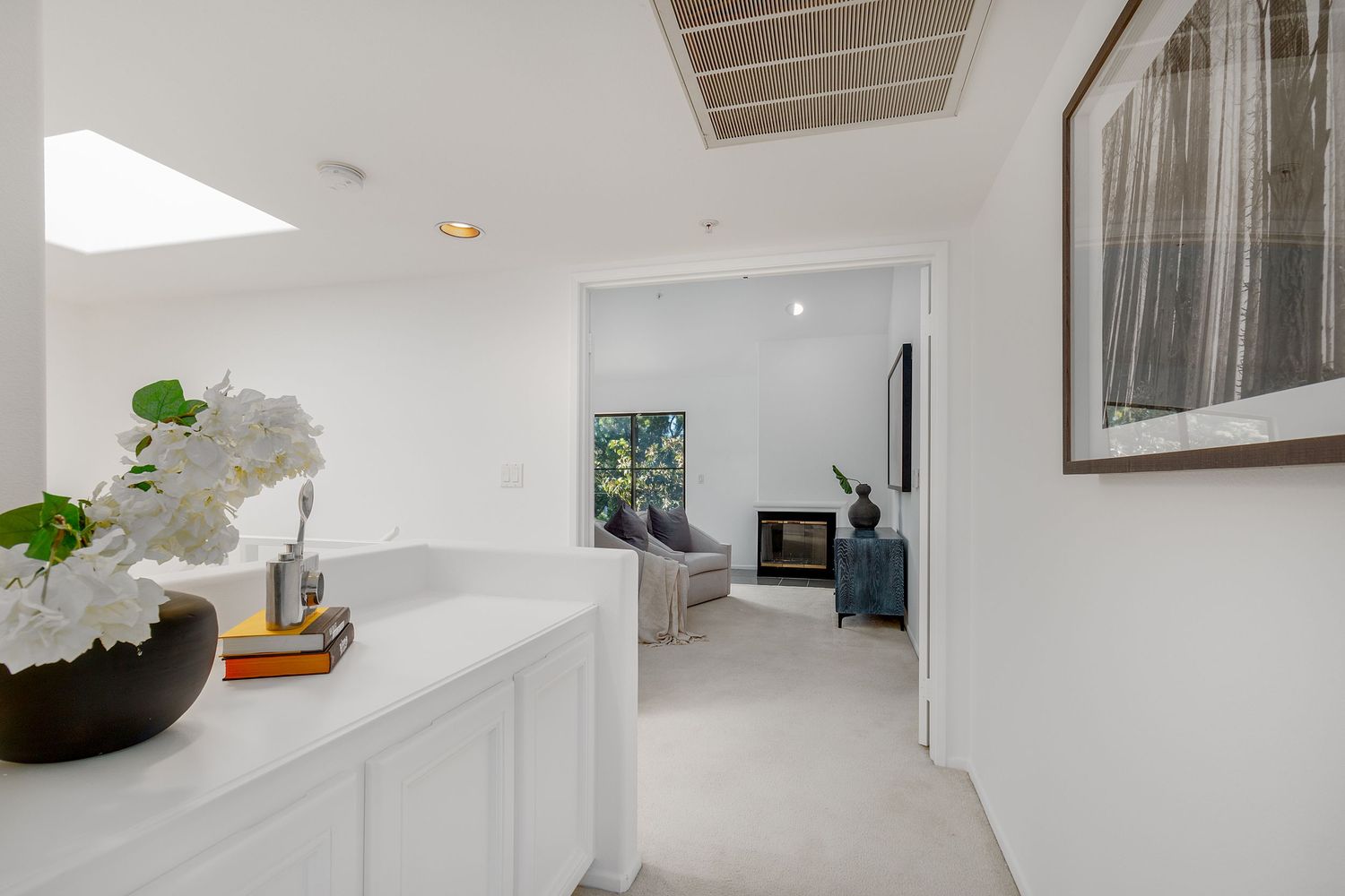 White modern hallway with skylight, built-in storage, and minimalist decor.