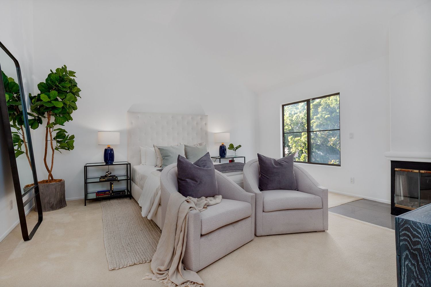 Contemporary living room with grey seating, white walls, and abundant natural lighting from windows.