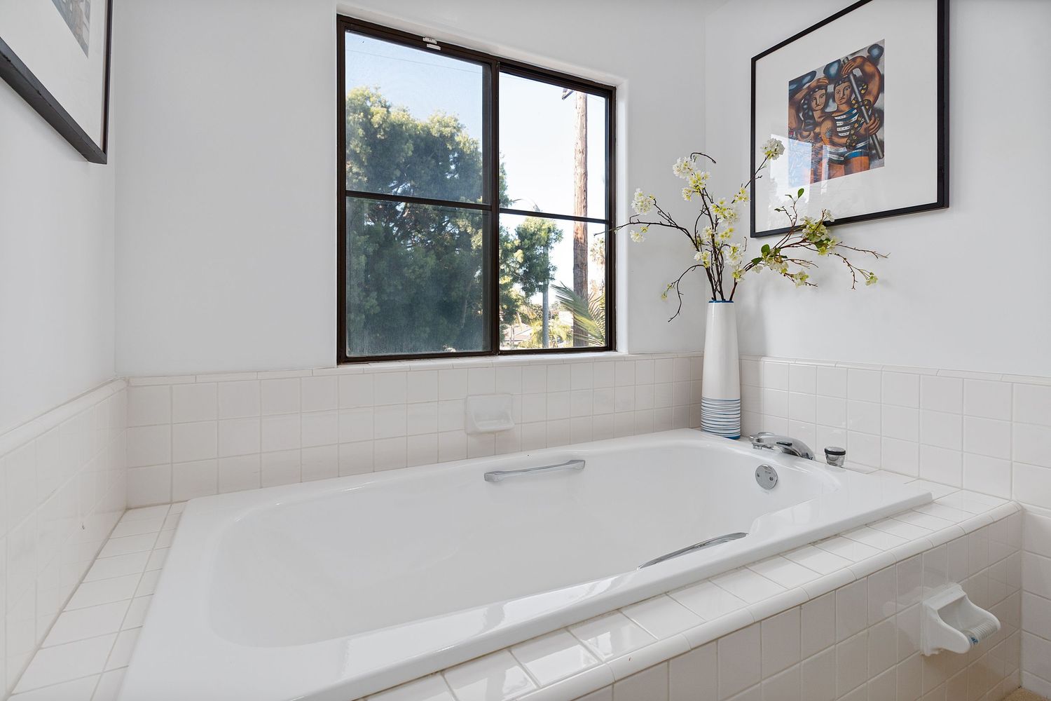 Bright and airy living space with white walls, high ceilings, and contemporary artwork displayed.