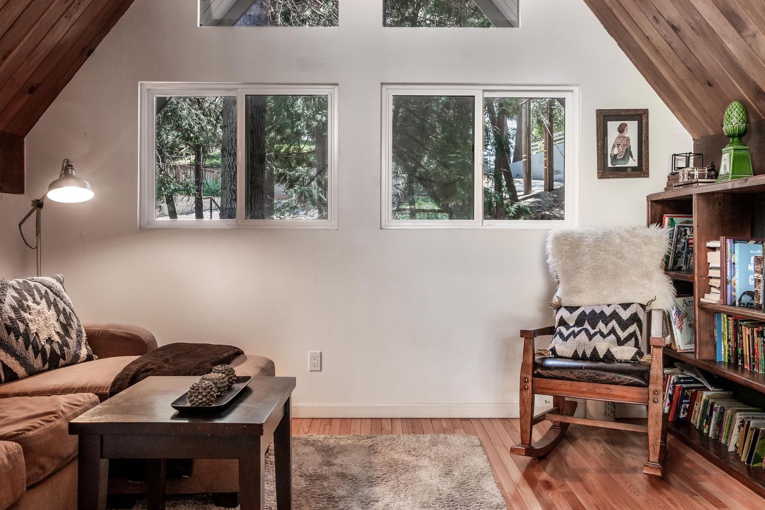 Cozy loft space with wooden ceiling beams and large windows offering natural lighting.