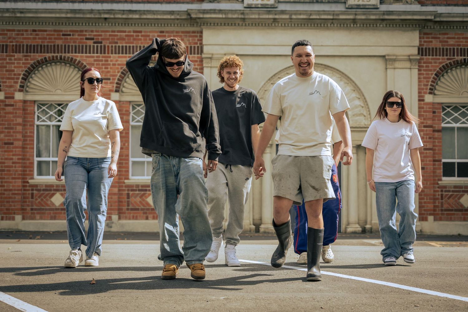 A group of young adults cross a street dressed in skater / street clothing