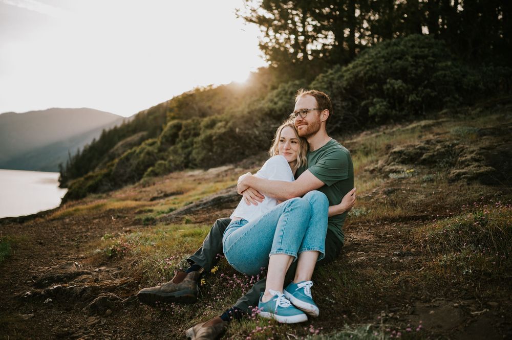 Soulful photo of couple sitting and hugging at Comox Lake bluff location, peaceful moment during engagement photoshoot