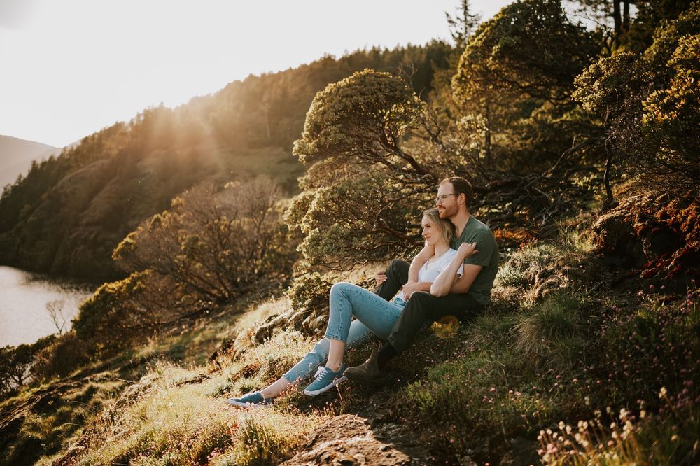 Beautiful photo of engagement session couple sitting with each other beside Comox Lake on the bluffs during golden hour on Vancouver Island
