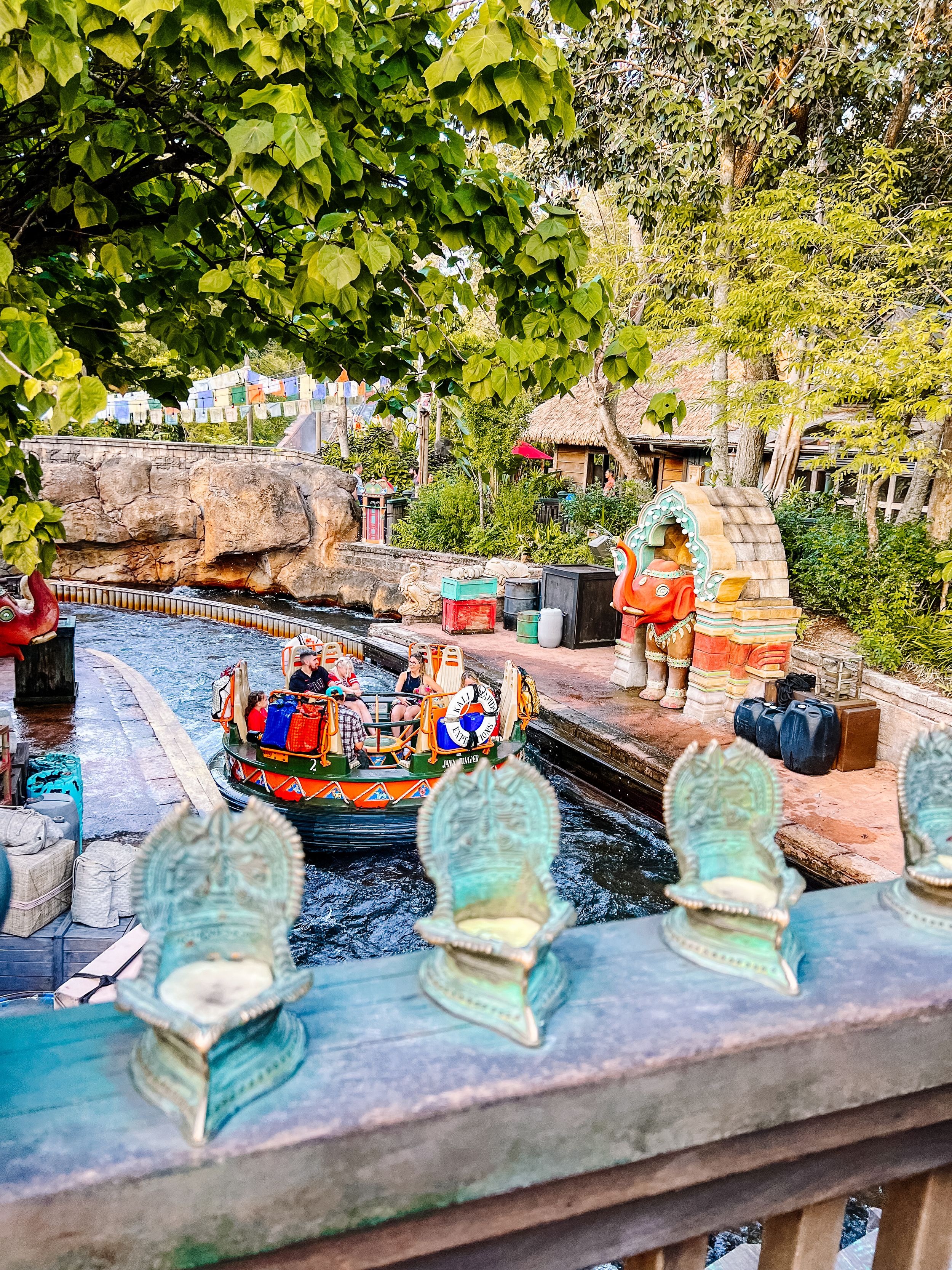 Theme park water ride with small boats and decorative glass bottles along the edge of a winding canal.