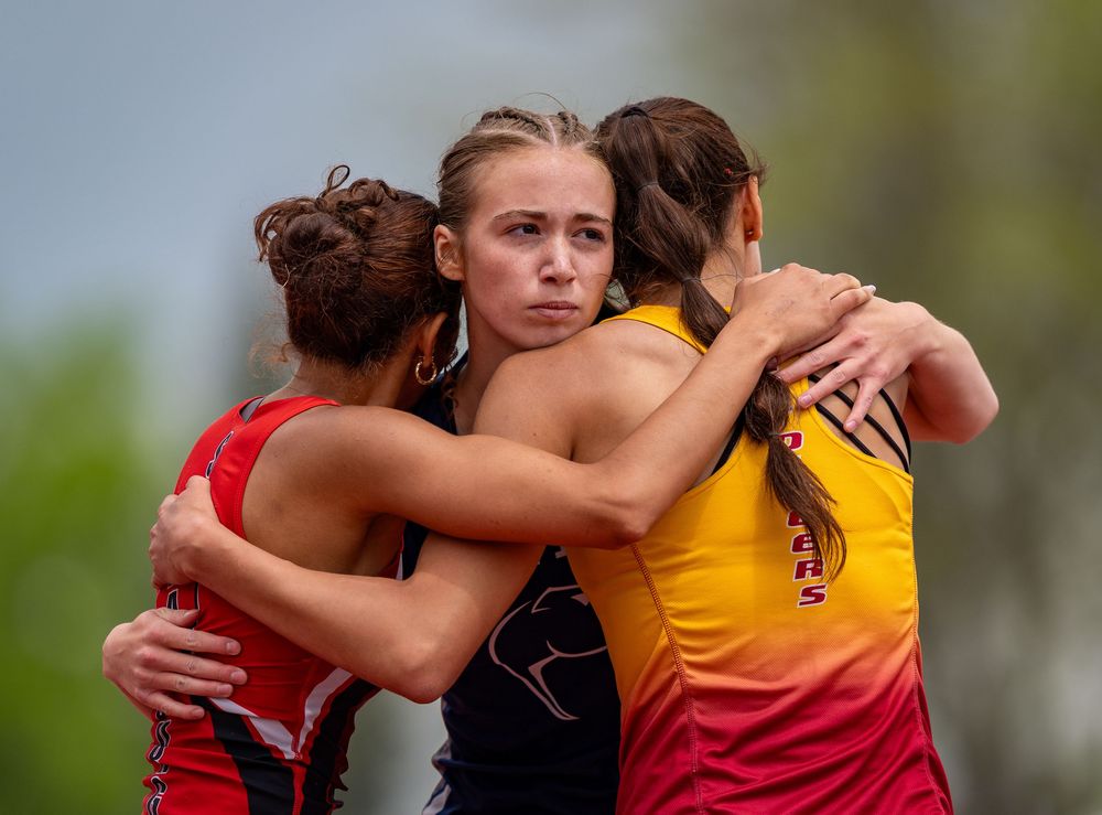 Athletes share emotional group hug after competition wearing red and yellow uniforms.