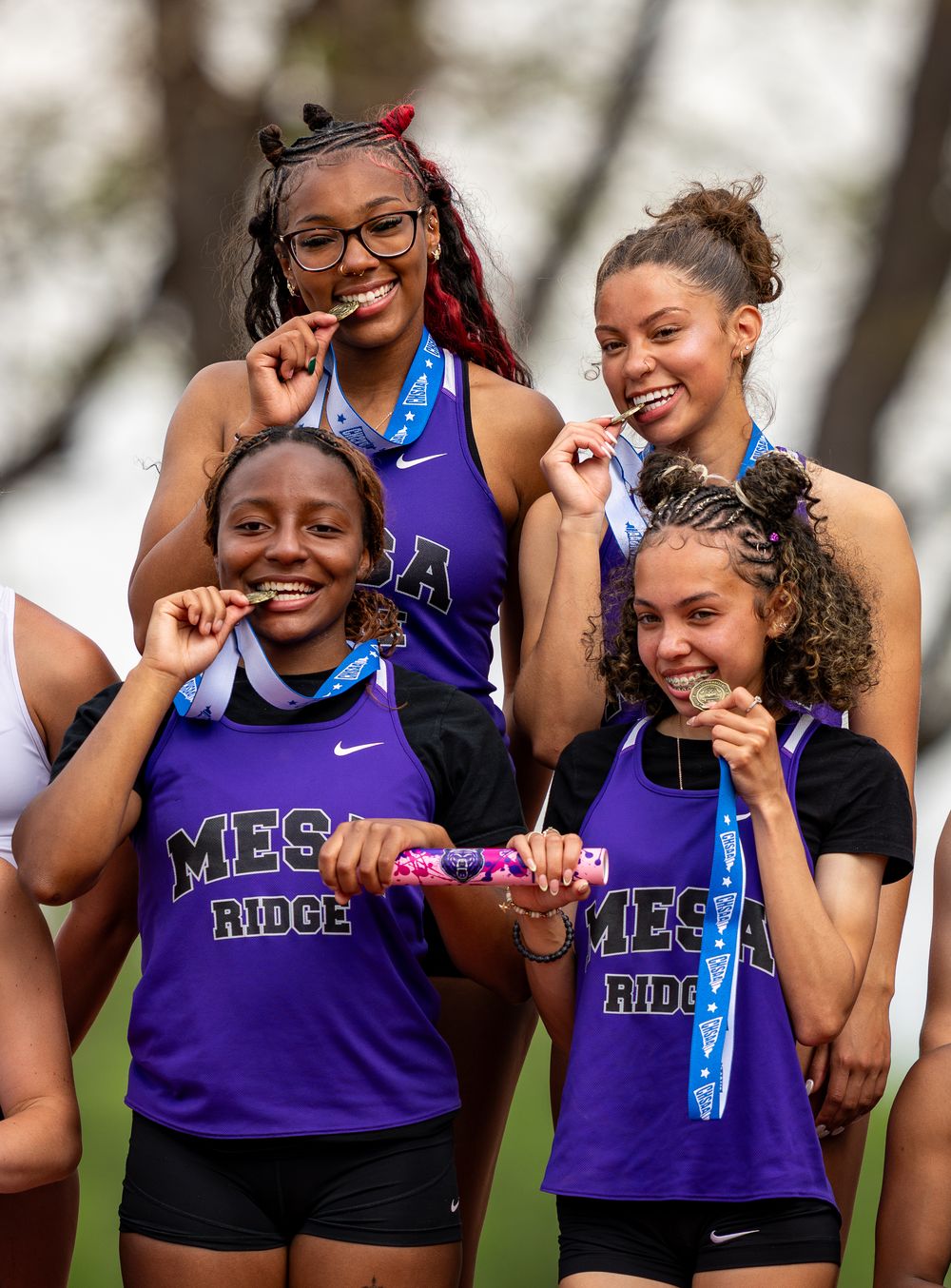 Track team members in purple uniforms celebrate together after competition.