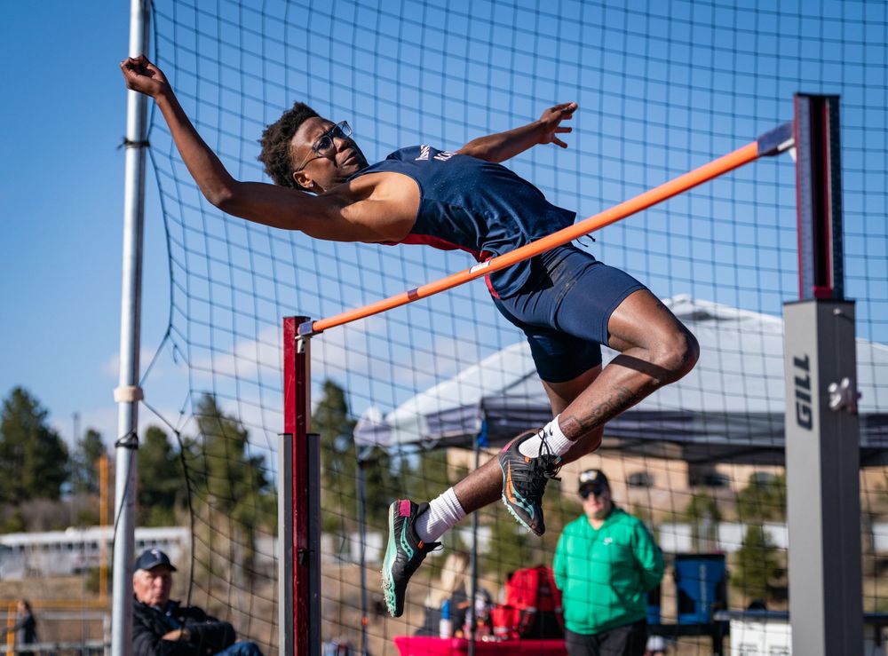 High school athlete performs high jump attempt clearing the bar at track meet.