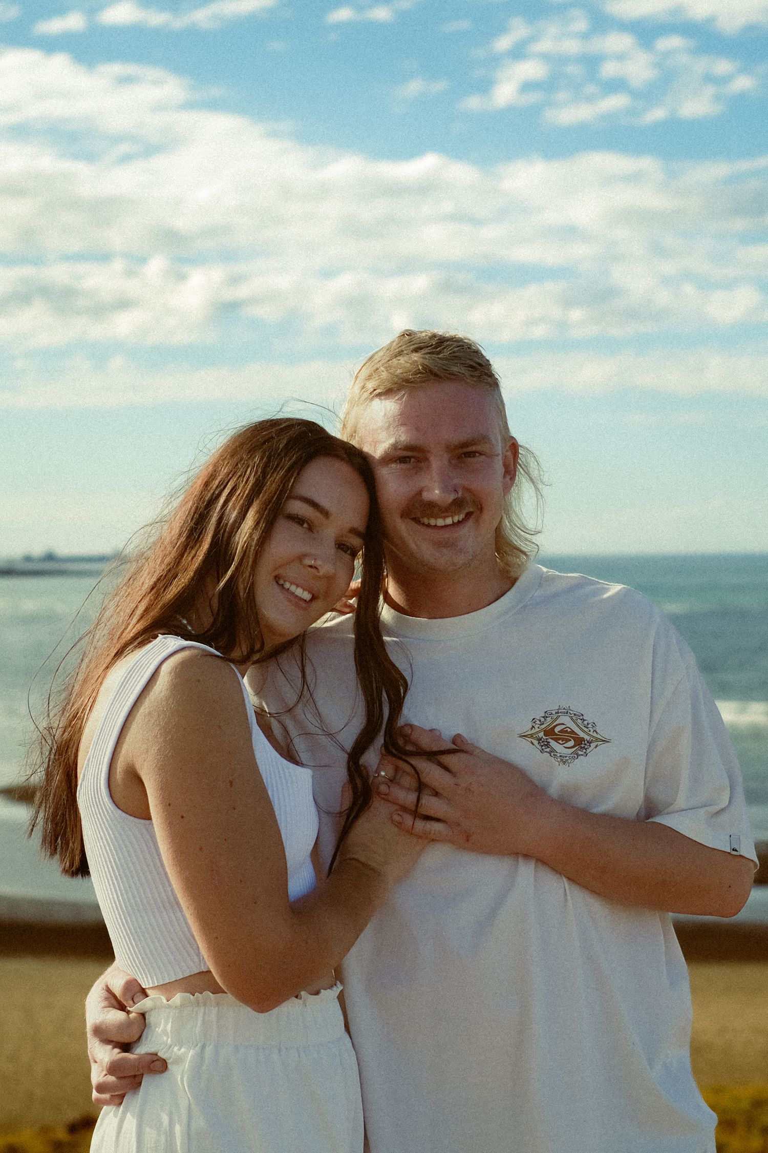 A happy couple sharing loving moments against a bright blue sky backdrop.