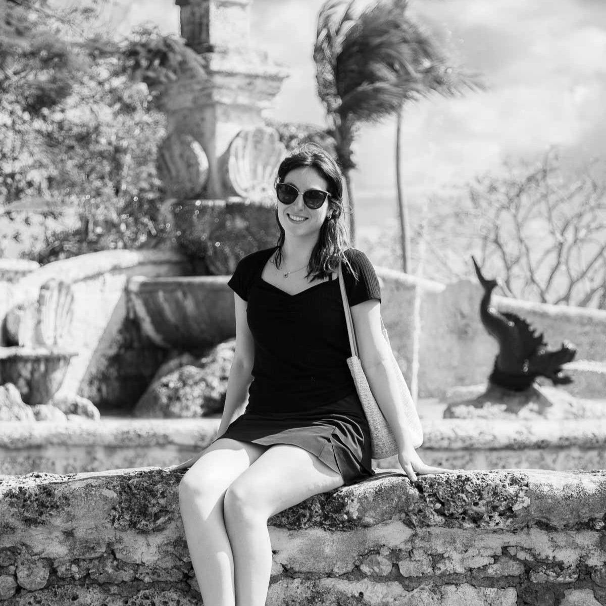 A portrait of a beautiful woman sitting on a stone wall while travelling in the Dominican Republic on vacation.
