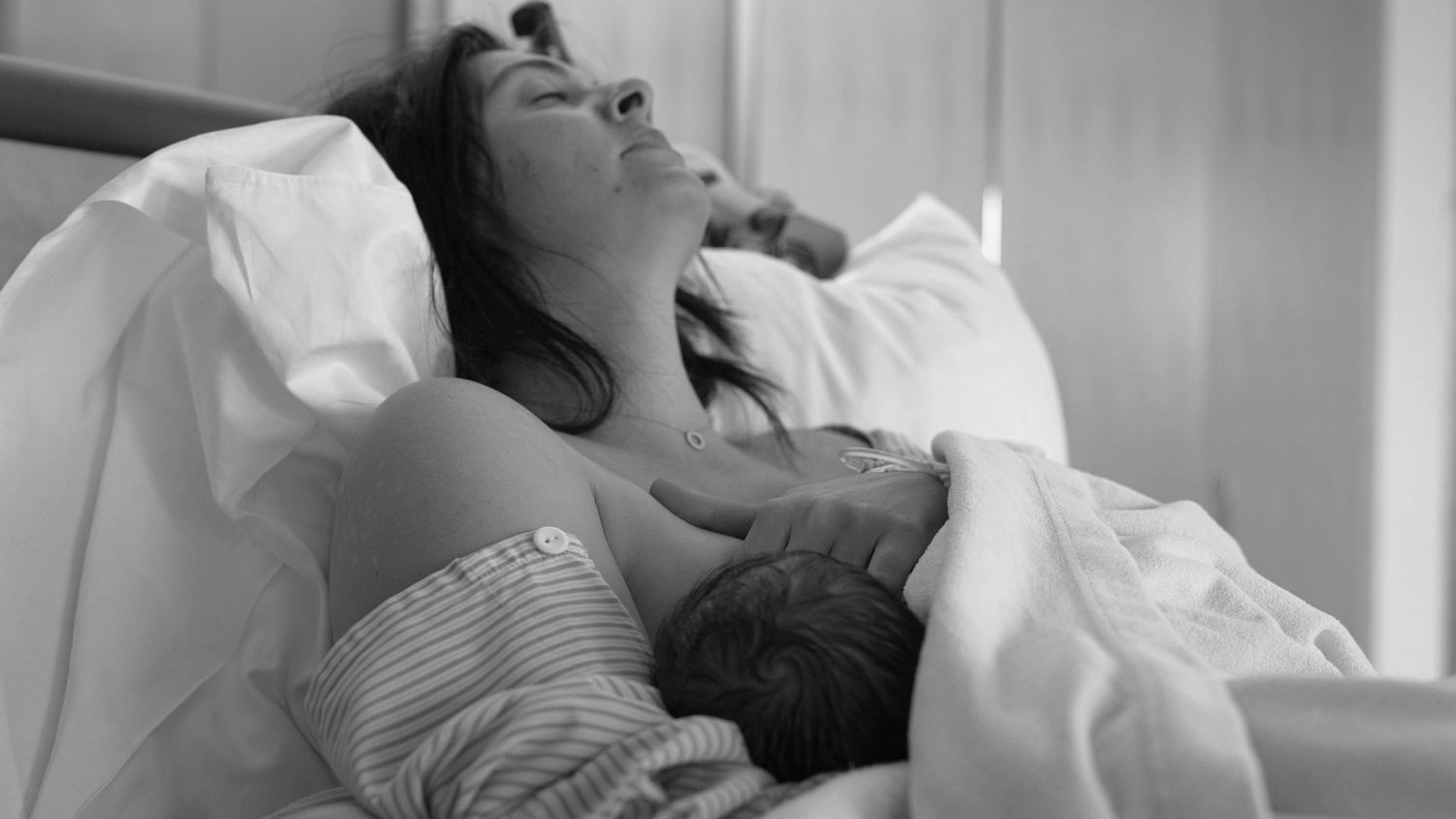 Kaiser labor and delivery. First latch. A precious moment between mother and newborn baby showing skin-to-skin bonding after birth.