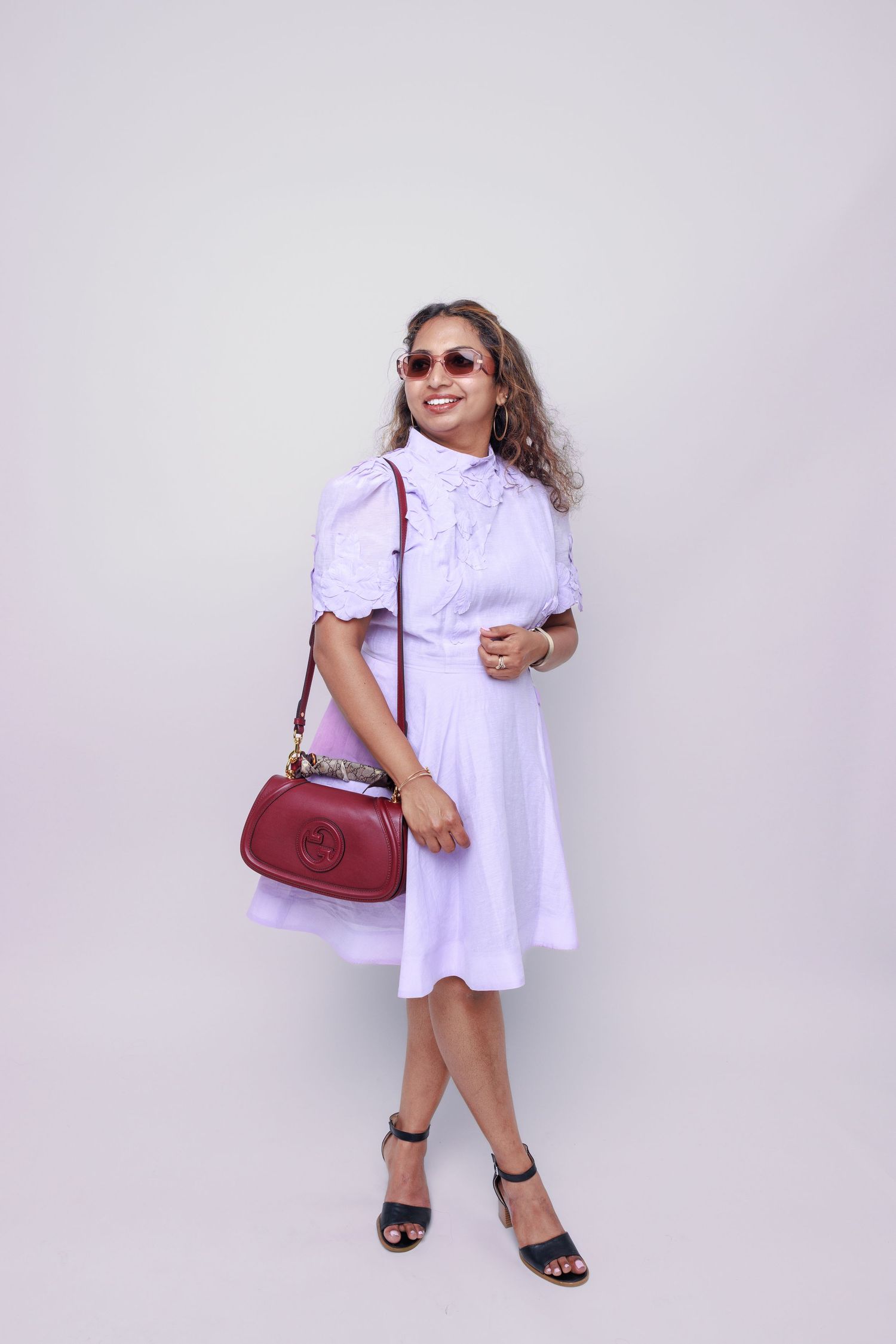 Fashion portraits of a person in white dress with red handbag and sunglasses.