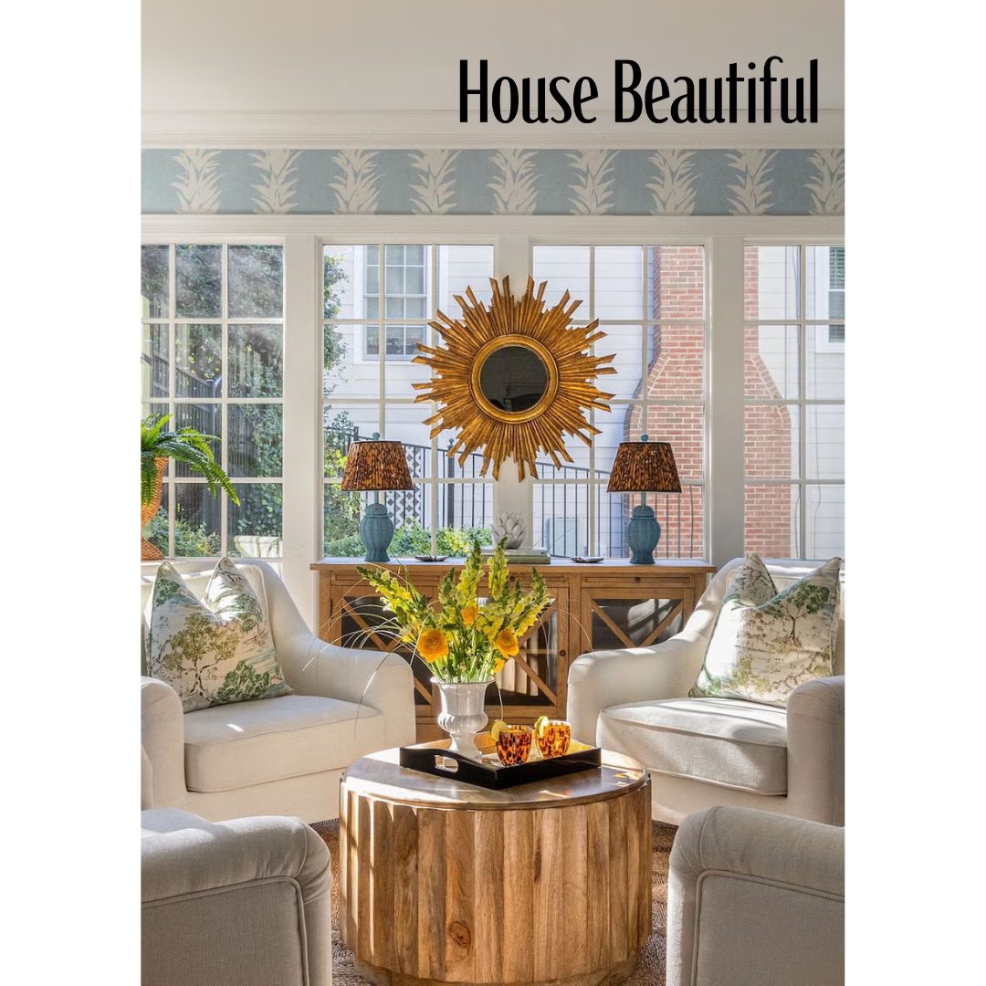 Heather Ison Photography for House Beautiful. Bright sunroom with white armchairs, decorative sunburst mirror, yellow floral centerpiece.