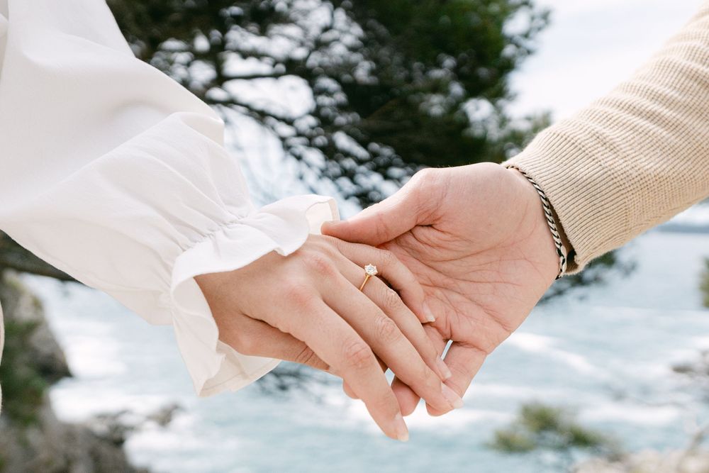 Two hands gently touching in a romantic moment outdoors with snowy winter scenery in the background.